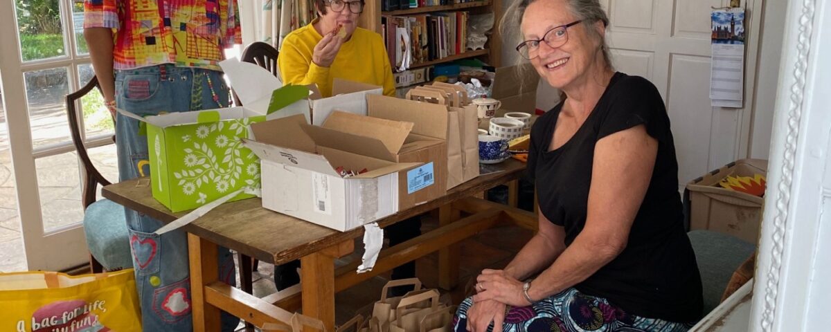 Three people at a table packing paper bags