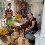 Three people at a table packing paper bags