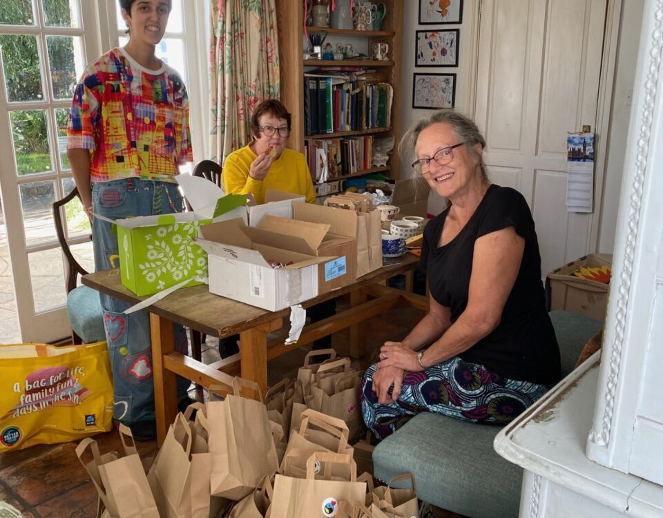 Three people at a table packing paper bags